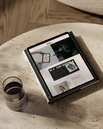 Tablet displaying a website on a stone surface with a glass of dark liquid nearby