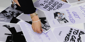 Two women discussing a project with a tablet displaying a website on a dark background.
