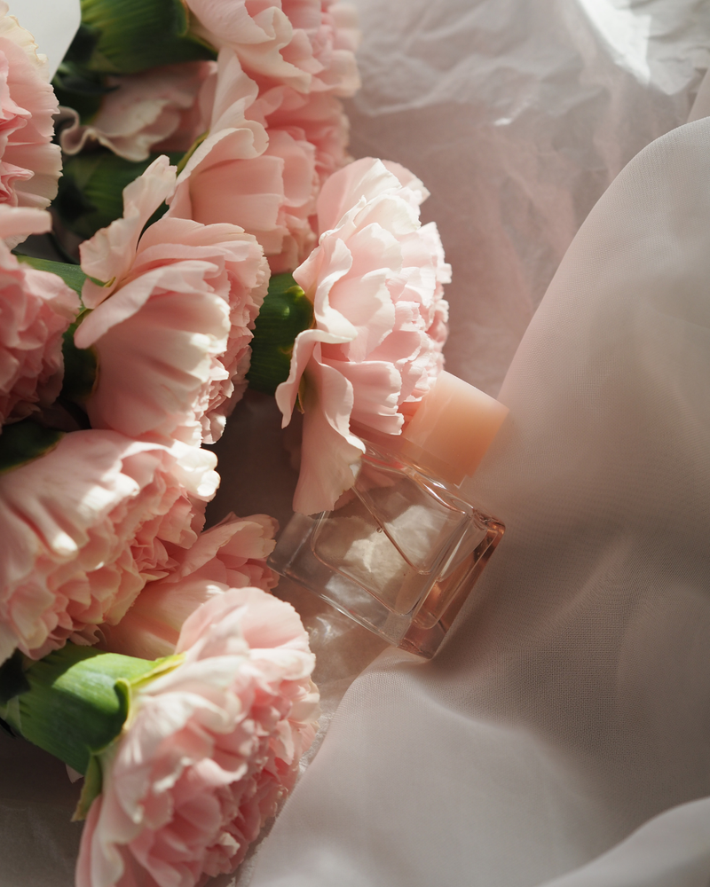 Pink perfume bottle with pink flowers on a white background